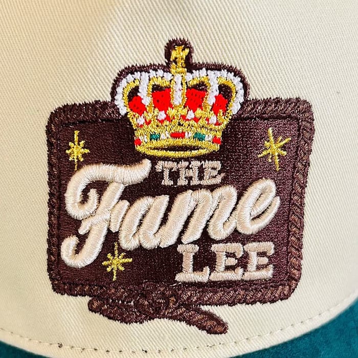 Close-up of the embroidered crown crest patch on a cream baseball cap